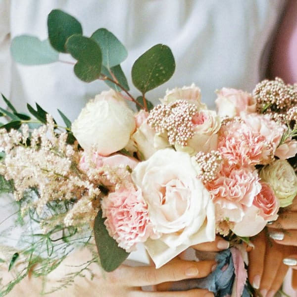 Hands holding a bouquet of roses.